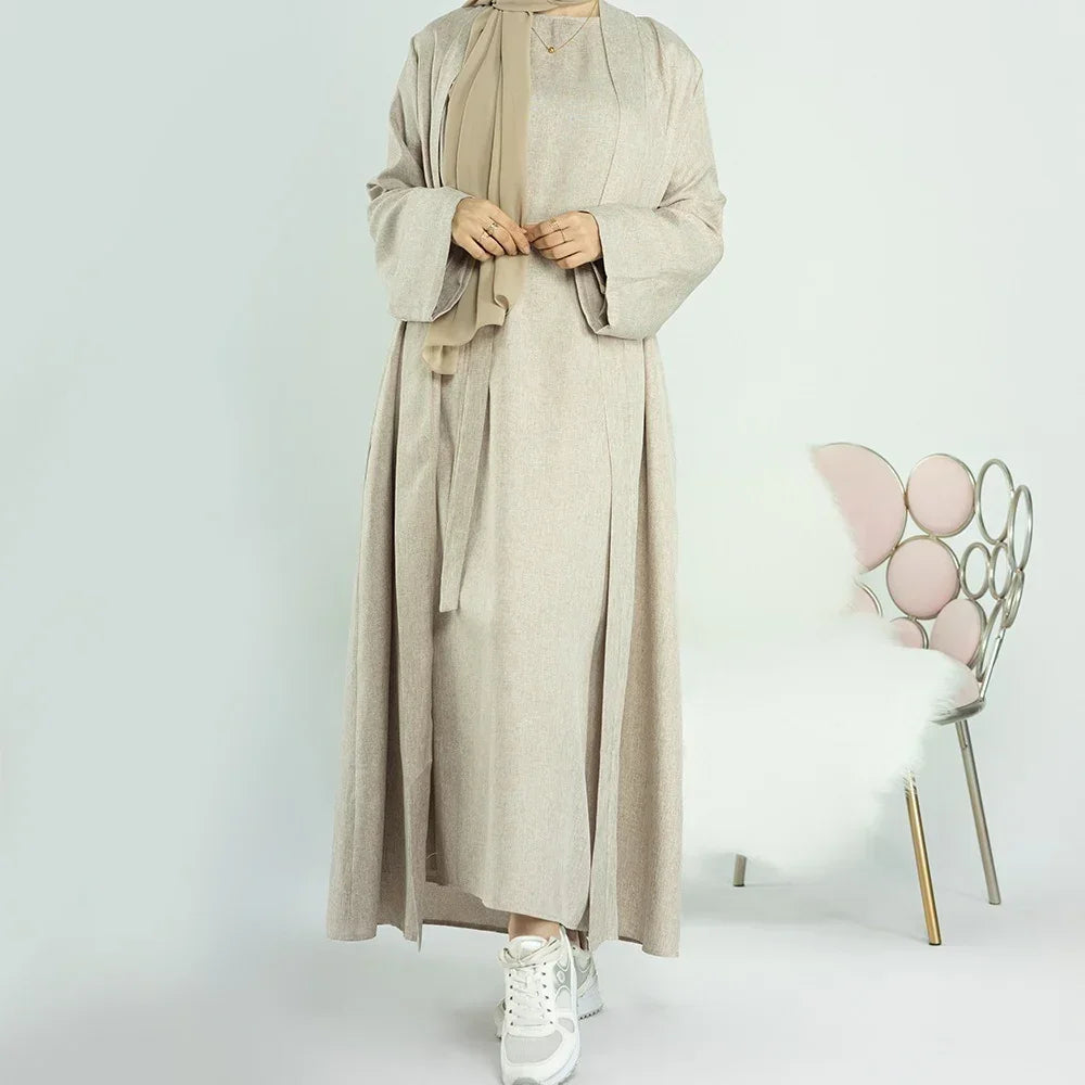 Woman wearing beige long modest abaya with scarf and white sneakers standing indoors